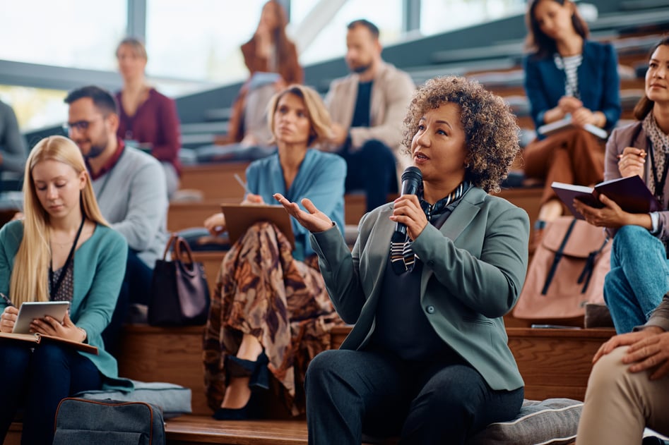 mature-businesswoman-using-microphone-while-speaking-from-audience-seminar