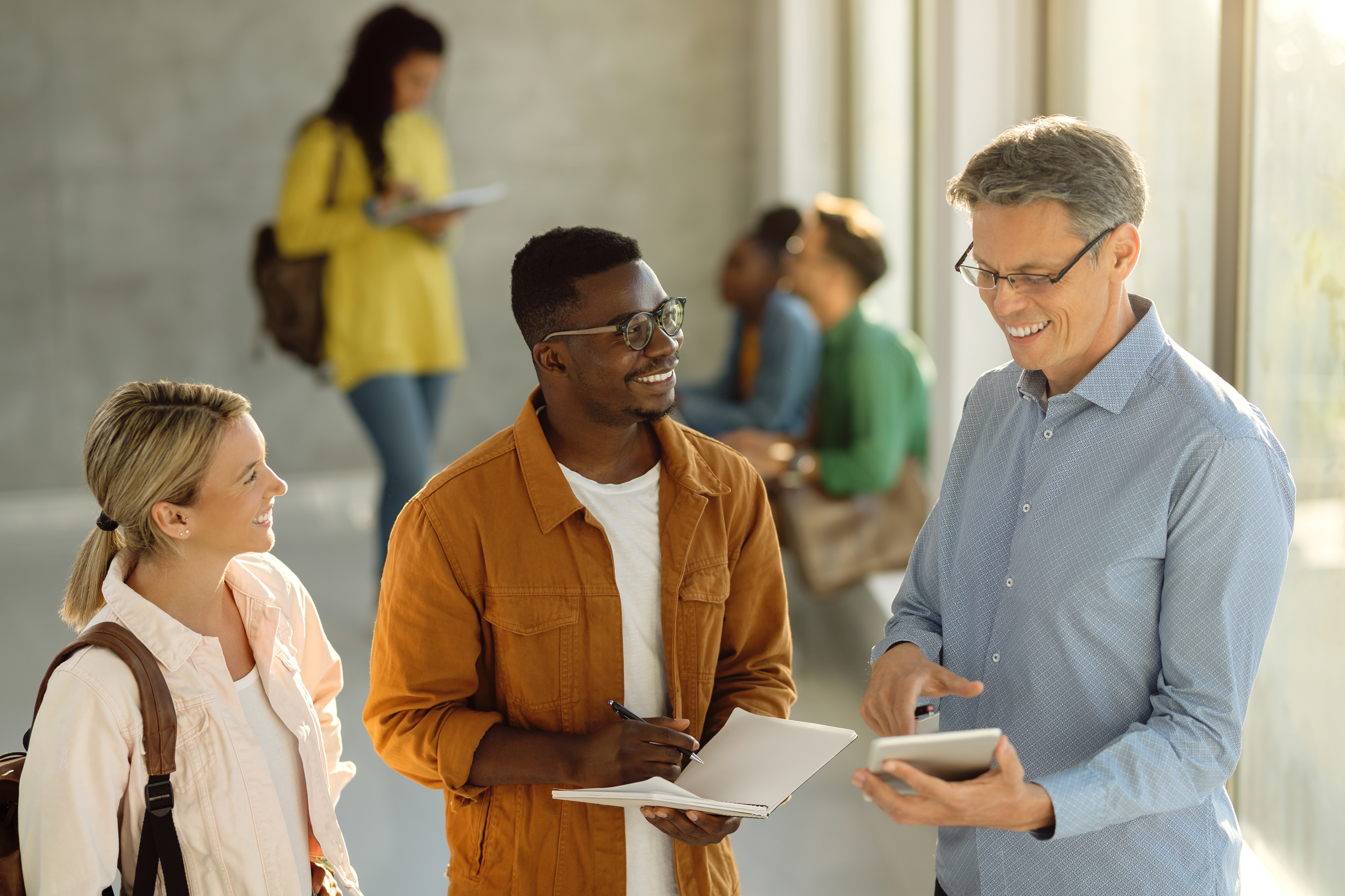 happy-students-their-professor-using-touchpad-university-hallway