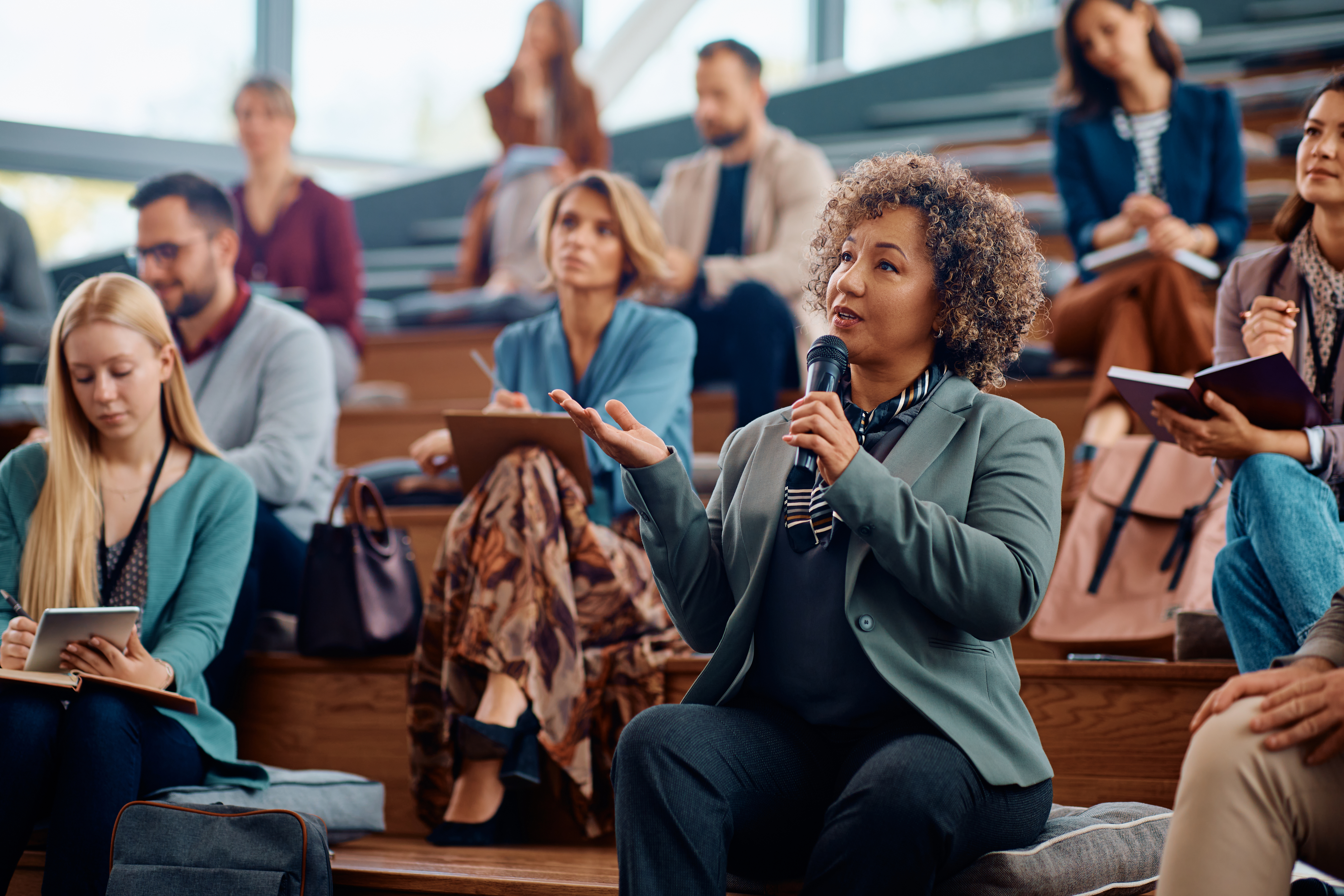 businesswoman-using-microphone-while-speaking-from-audience-seminar