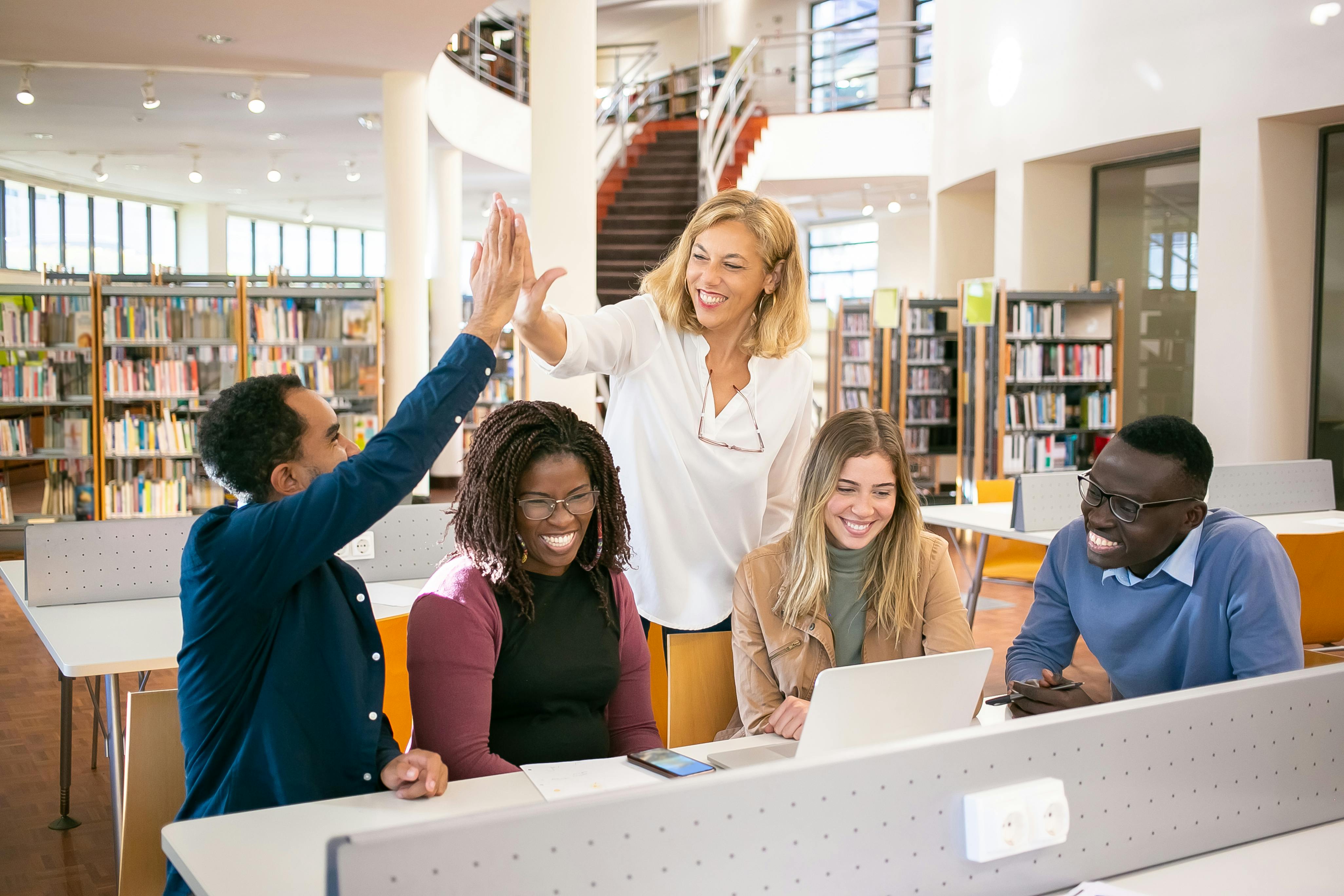 advisor high-fiving students in library